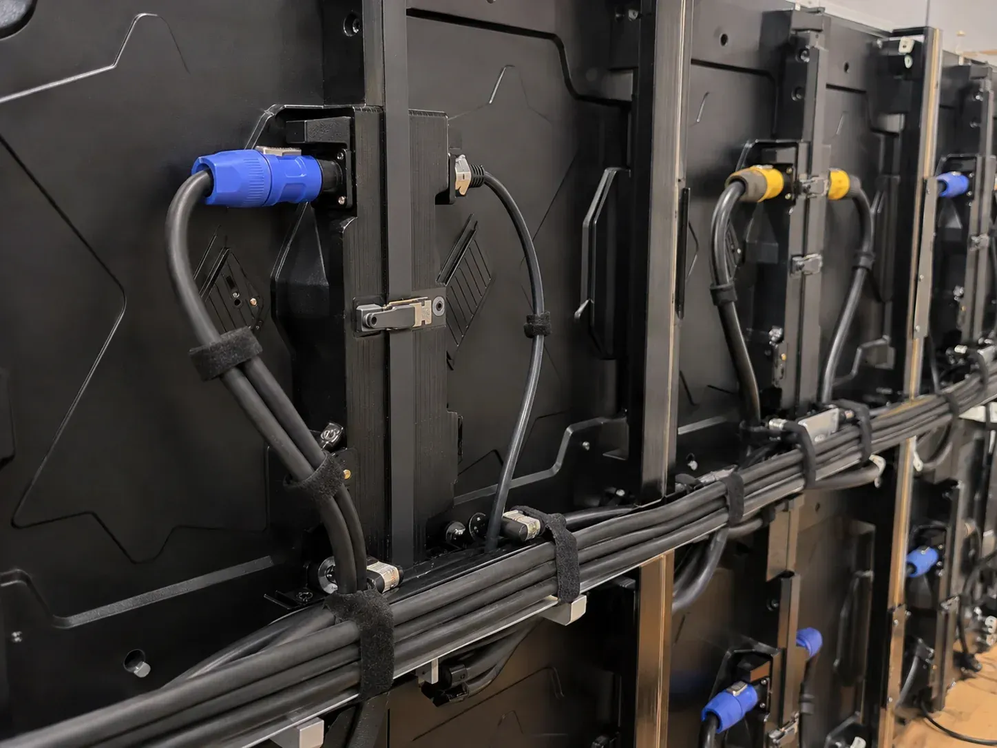 Technician installation work showing organized power and data connections at the back of an LED wall.